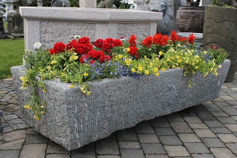 Pflanztrog aus Naturstein mit Bepflanzung für dei Gartengestaltung.