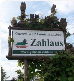 Werbeschild der Firma Zahlaus mit geschnitzten Eulen.